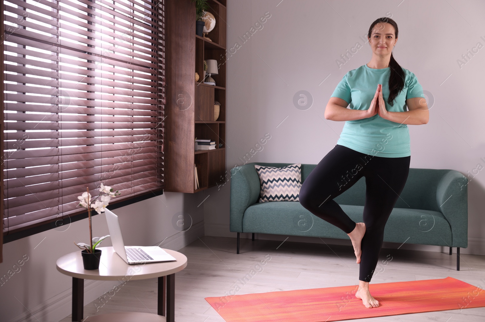 Photo of Overweight woman practicing yoga at home, space for text