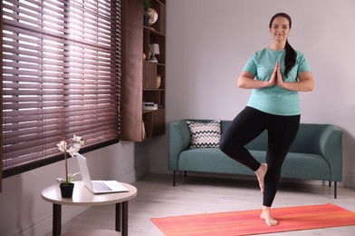 Photo of Overweight woman practicing yoga at home, space for text