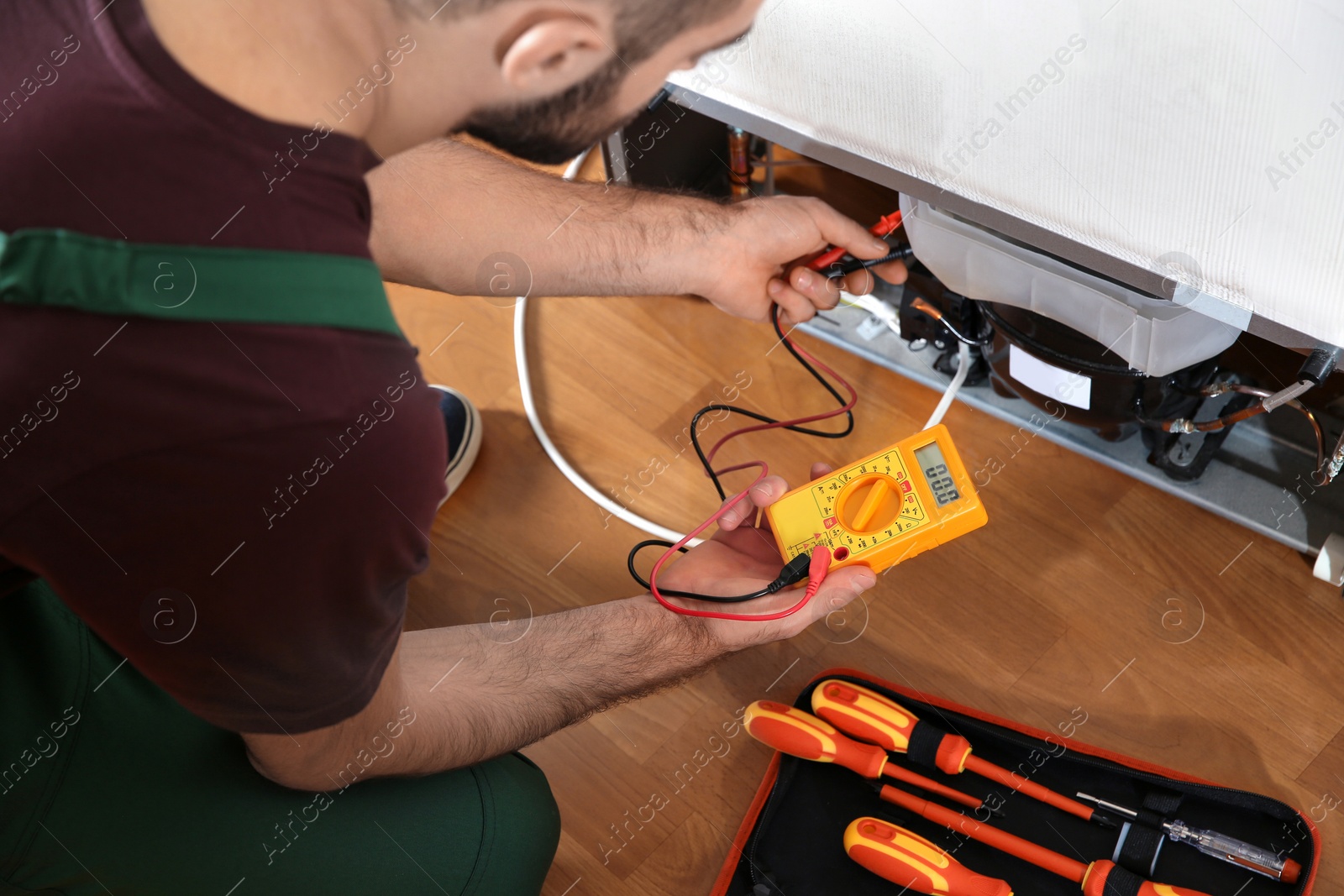 Photo of Male technician repairing broken refrigerator indoors, closeup