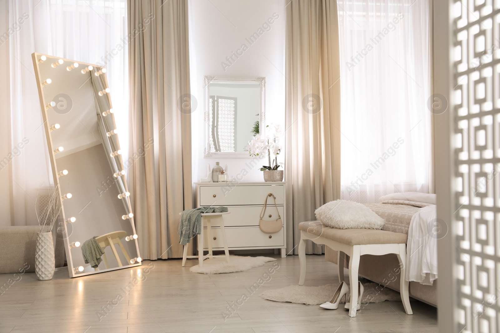 Photo of Large mirror with light bulbs and chest of drawers in bedroom. Interior design