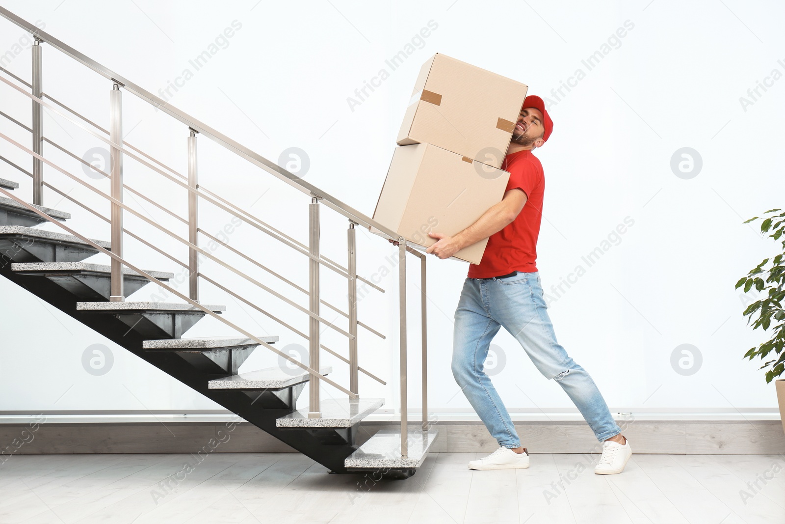 Photo of Man in uniform carrying carton boxes indoors. Posture concept