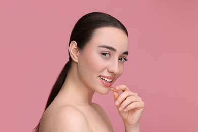 Photo of Beautiful young woman with vitamin pill on pink background