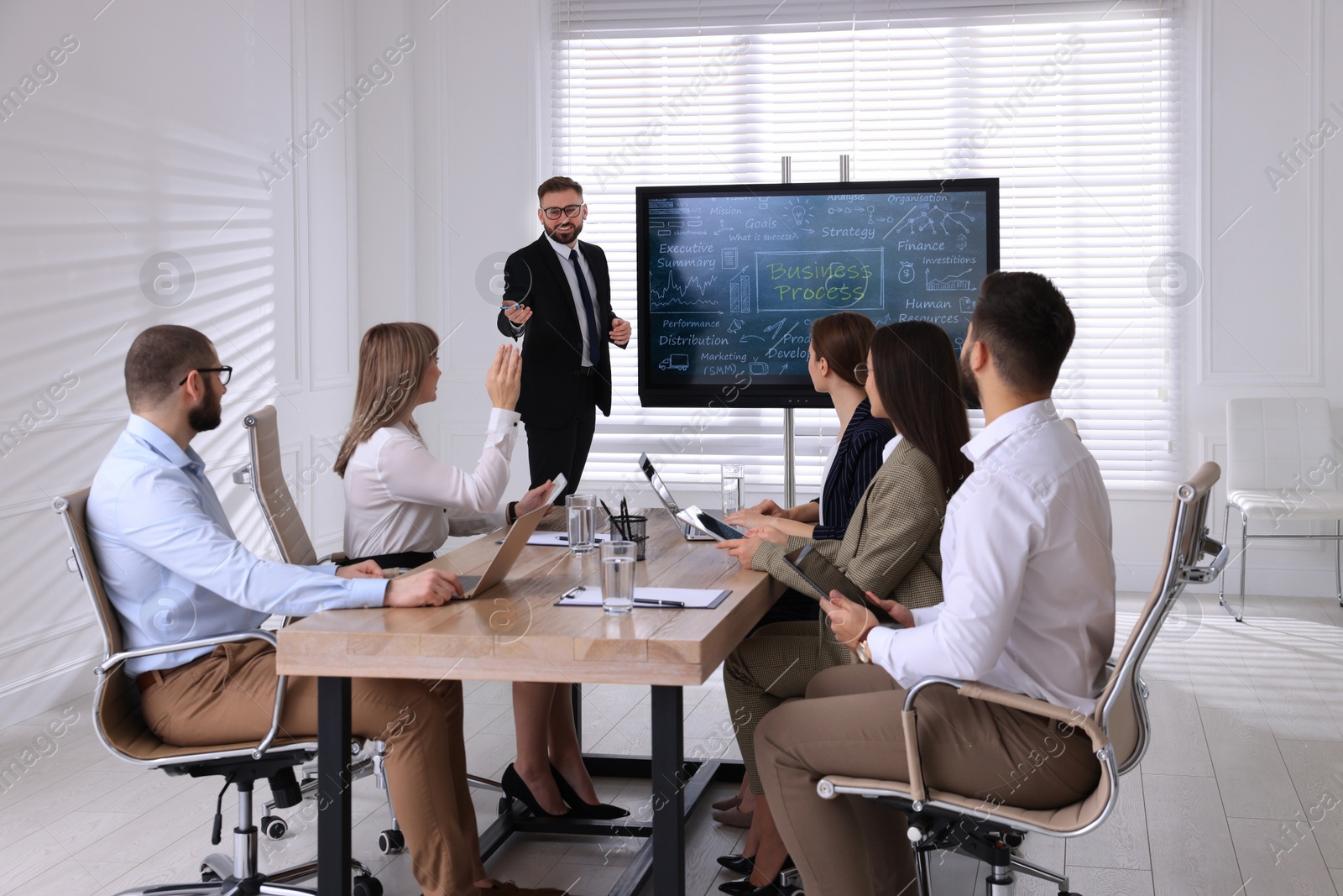 Photo of Business trainer near interactive board in meeting room during presentation