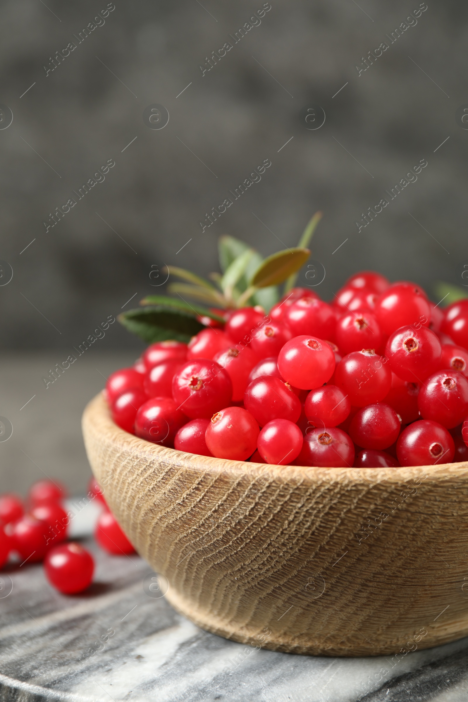 Photo of Tasty ripe cranberries on grey marble board, closeup