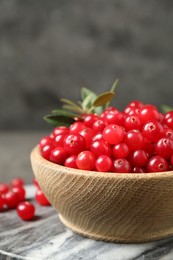 Tasty ripe cranberries on grey marble board, closeup