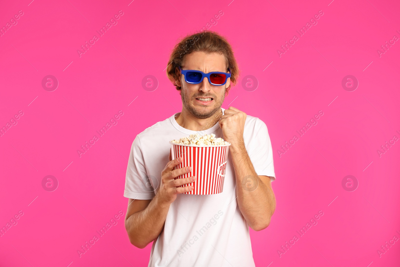 Photo of Emotional man with 3D glasses and popcorn during cinema show on color background