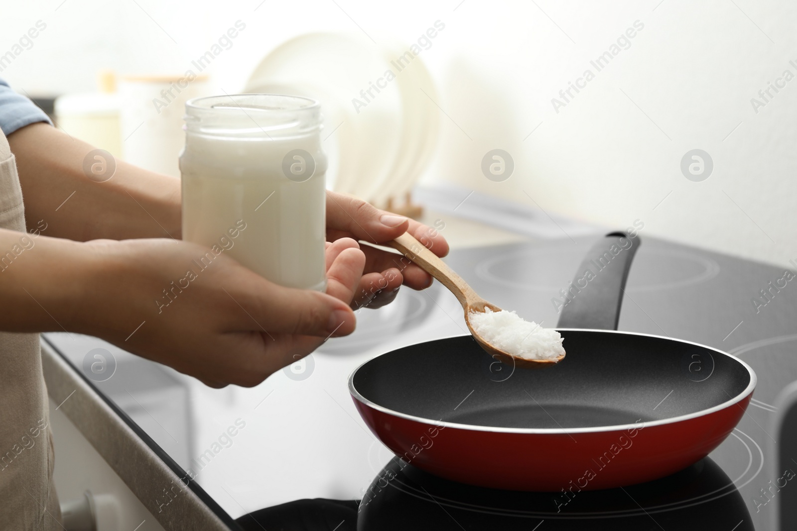 Photo of Woman cooking with coconut oil on induction stove, closeup