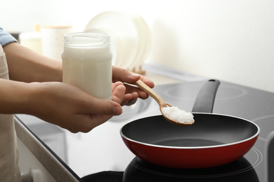 Photo of Woman cooking with coconut oil on induction stove, closeup