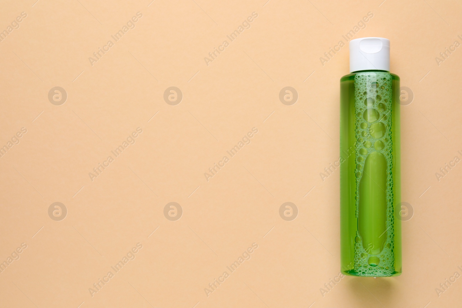 Photo of Micellar water on beige background, top view. Space for text