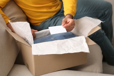 Photo of Young man holding greeting card near parcel with Christmas gift, closeup