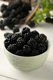 Photo of Bowl with fresh ripe blackberries on white wooden table