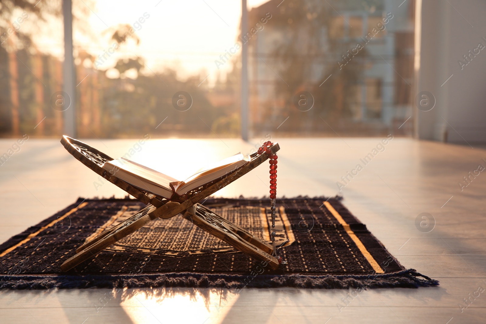 Photo of Rehal with open Quran and Muslim prayer beads on rug indoors. Space for text