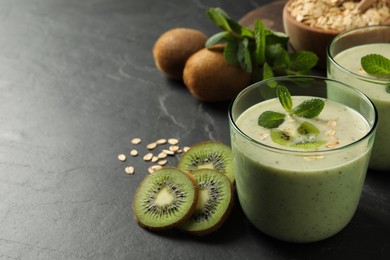 Photo of Glass of tasty kiwi smoothie with oatmeal on dark table. Space for text