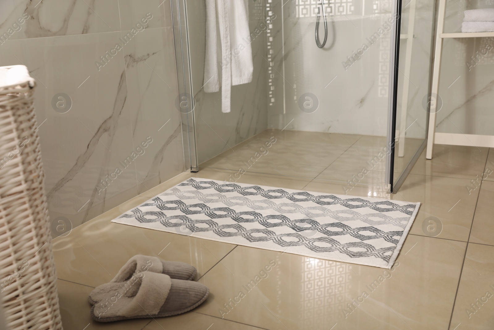 Photo of Soft bath mat and slippers on floor in bathroom