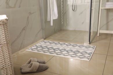 Photo of Soft bath mat and slippers on floor in bathroom