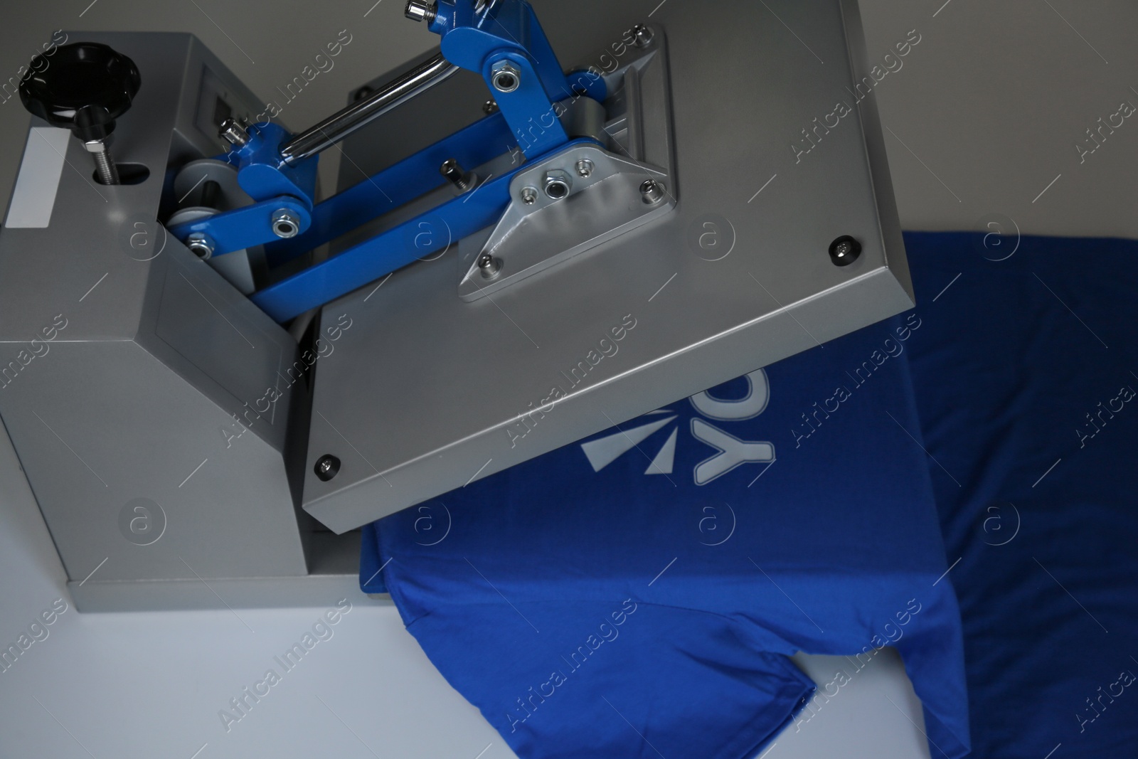 Photo of Printing logo. Heat press with blue t-shirt on white table