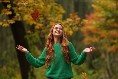 Photo of Autumn vibes. Happy woman throwing leaves up in park