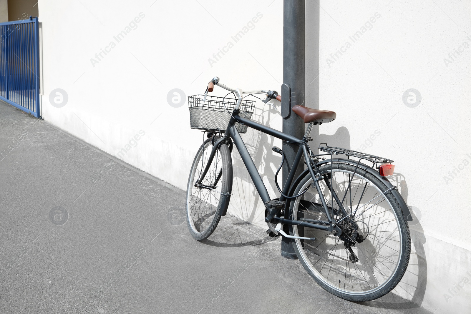 Photo of Vintage bicycle with basket locked to street post outdoors