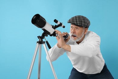 Photo of Senior astronomer with telescope on light blue background