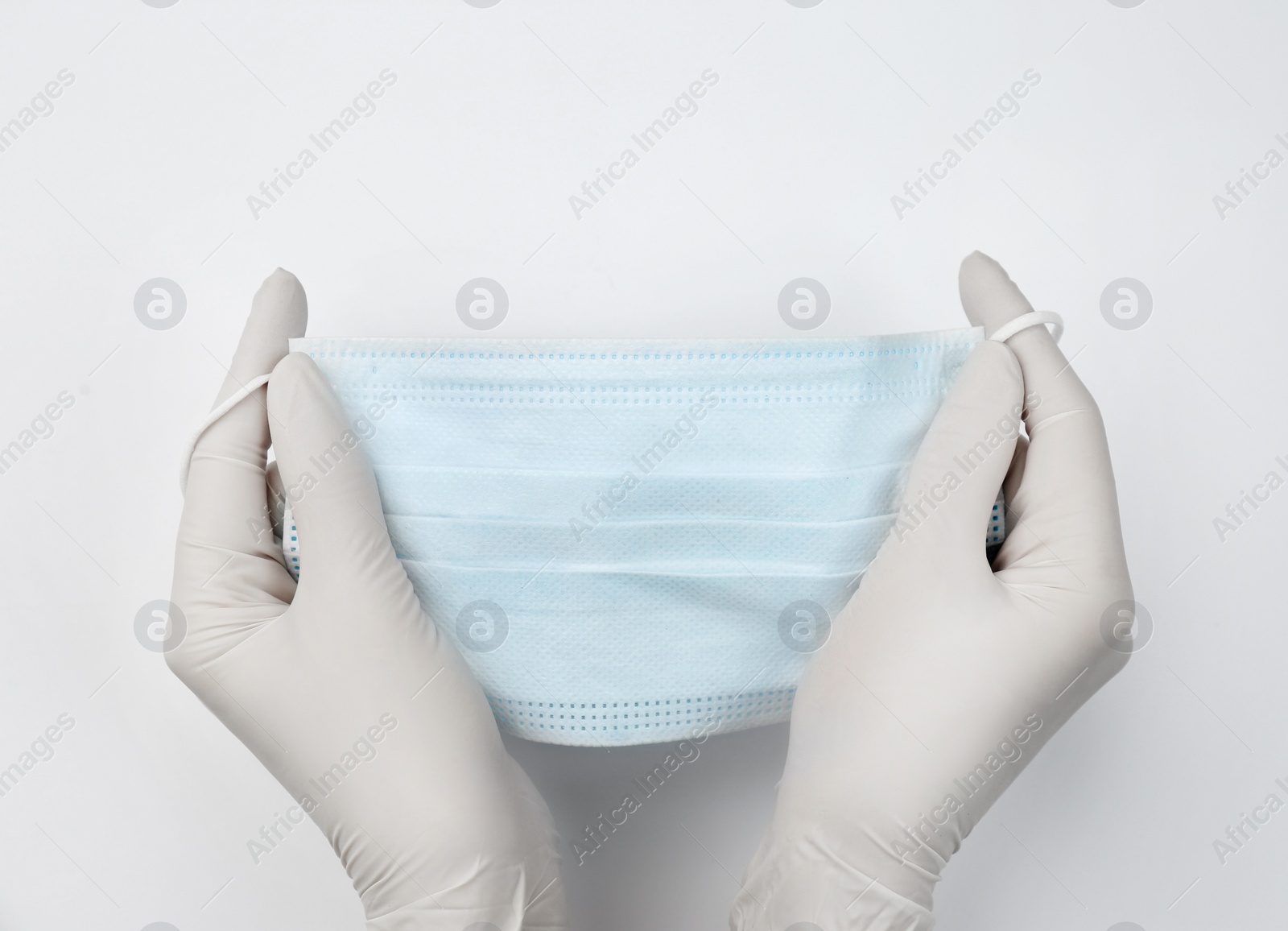 Photo of Doctor in medical gloves holding protective mask on white background, closeup