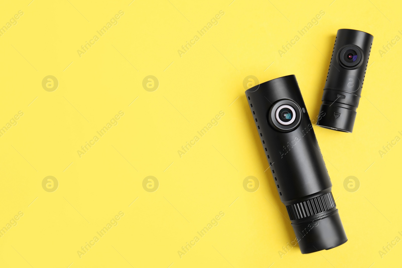 Photo of Black modern car cameras on yellow background, flat lay. Space for text