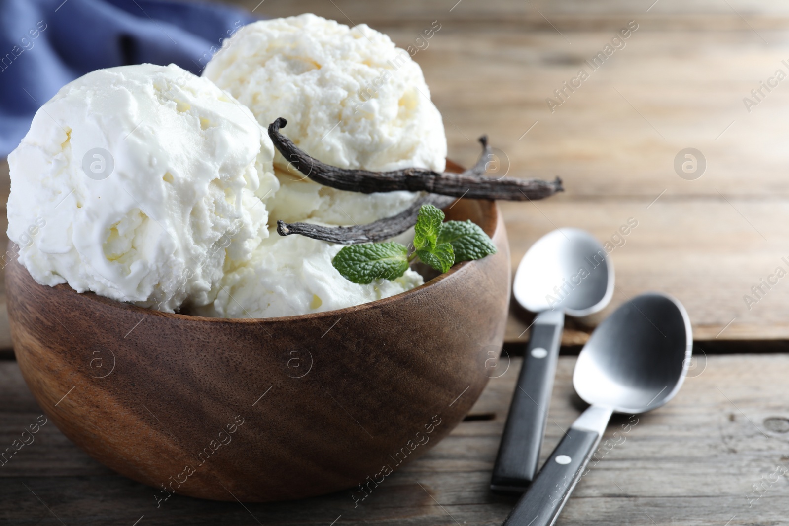 Photo of Yummy vanilla ice cream in bowl on wooden table, closeup
