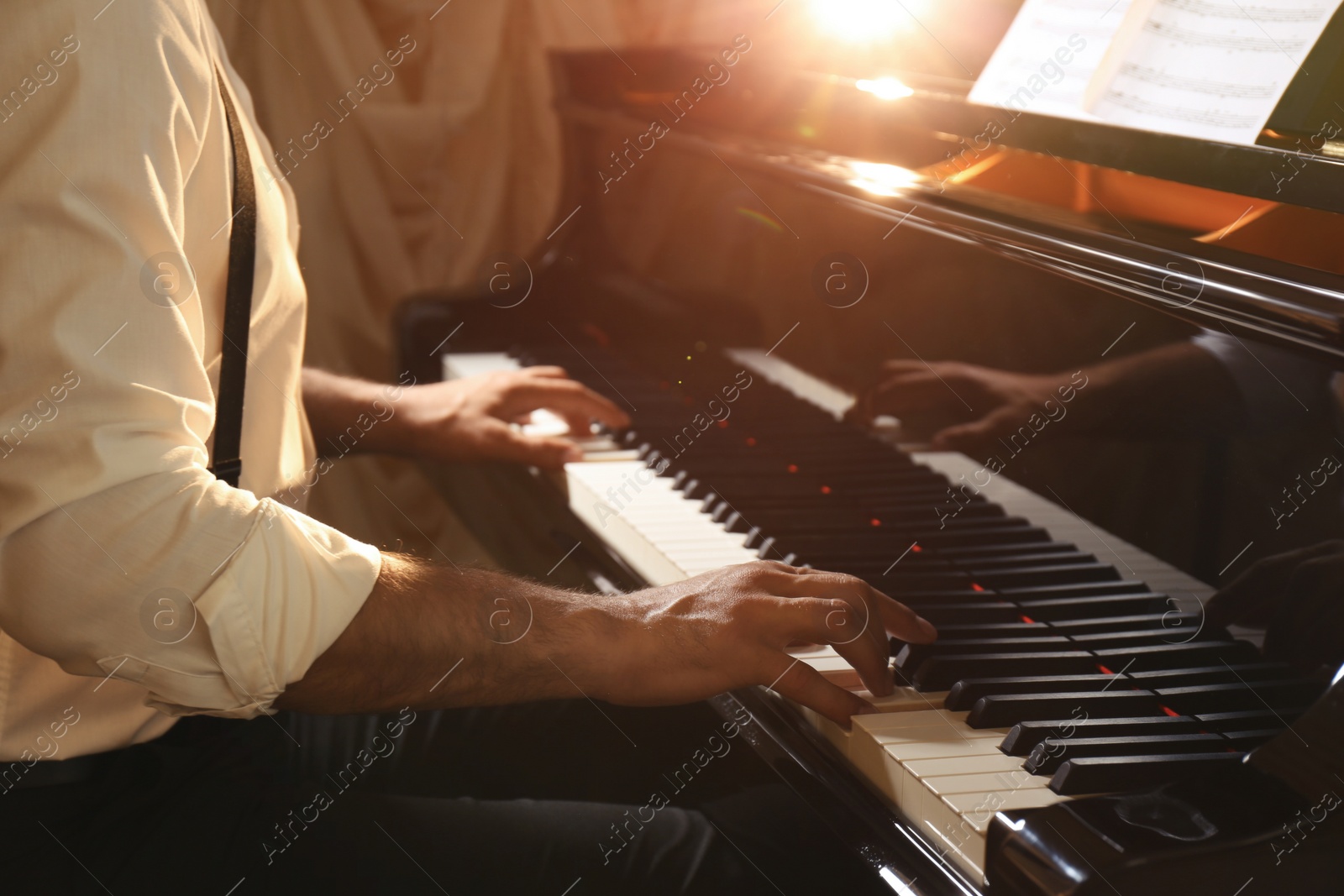 Photo of Man playing piano indoors, closeup. Talented musician