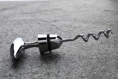 Photo of One metal corkscrew on grey textured table, closeup