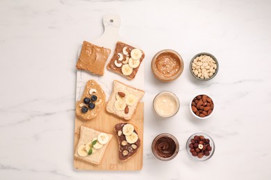 Photo of Toasts with different nut butters and products on white marble table, flat lay