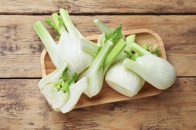 Photo of Fresh raw fennel bulbs on wooden table, top view