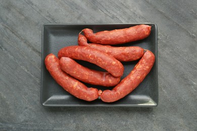Photo of Tasty sausages in plate on black table, top view. Meat product