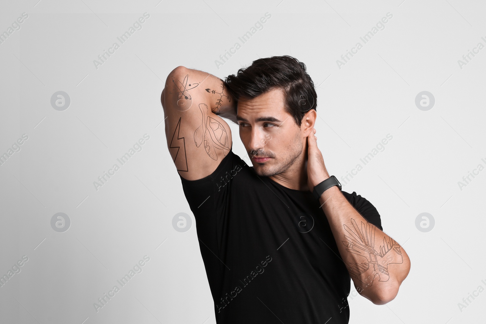 Image of Handsome man with beautiful tattoo sketches on light grey background