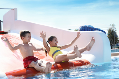 Photo of Happy children on slide at water park. Summer vacation