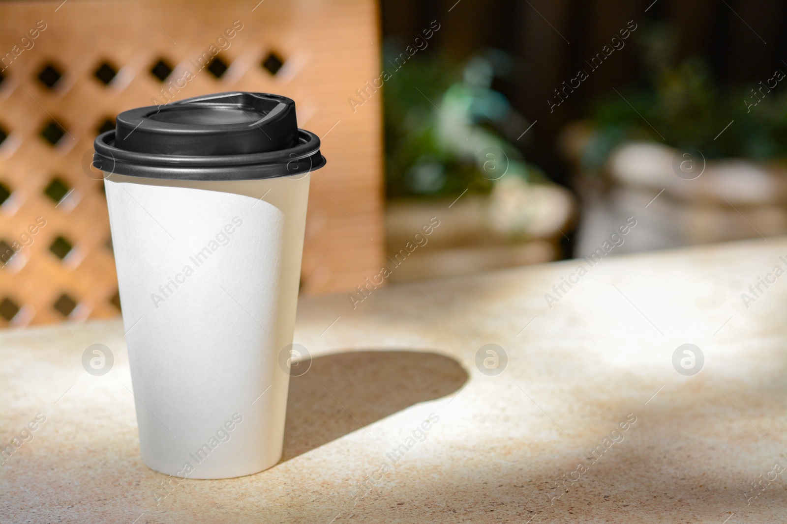 Photo of Takeaway coffee cup on beige table in cafe, space for text