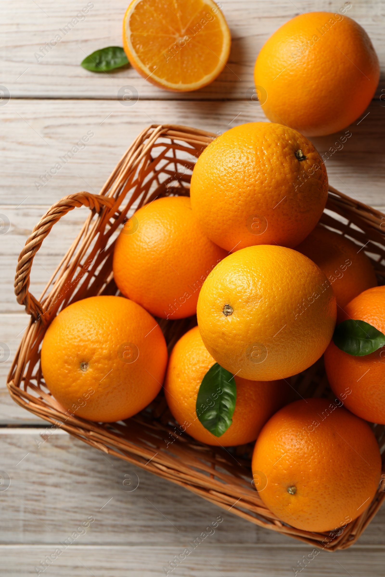 Photo of Many ripe oranges and green leaves on wooden table, top view