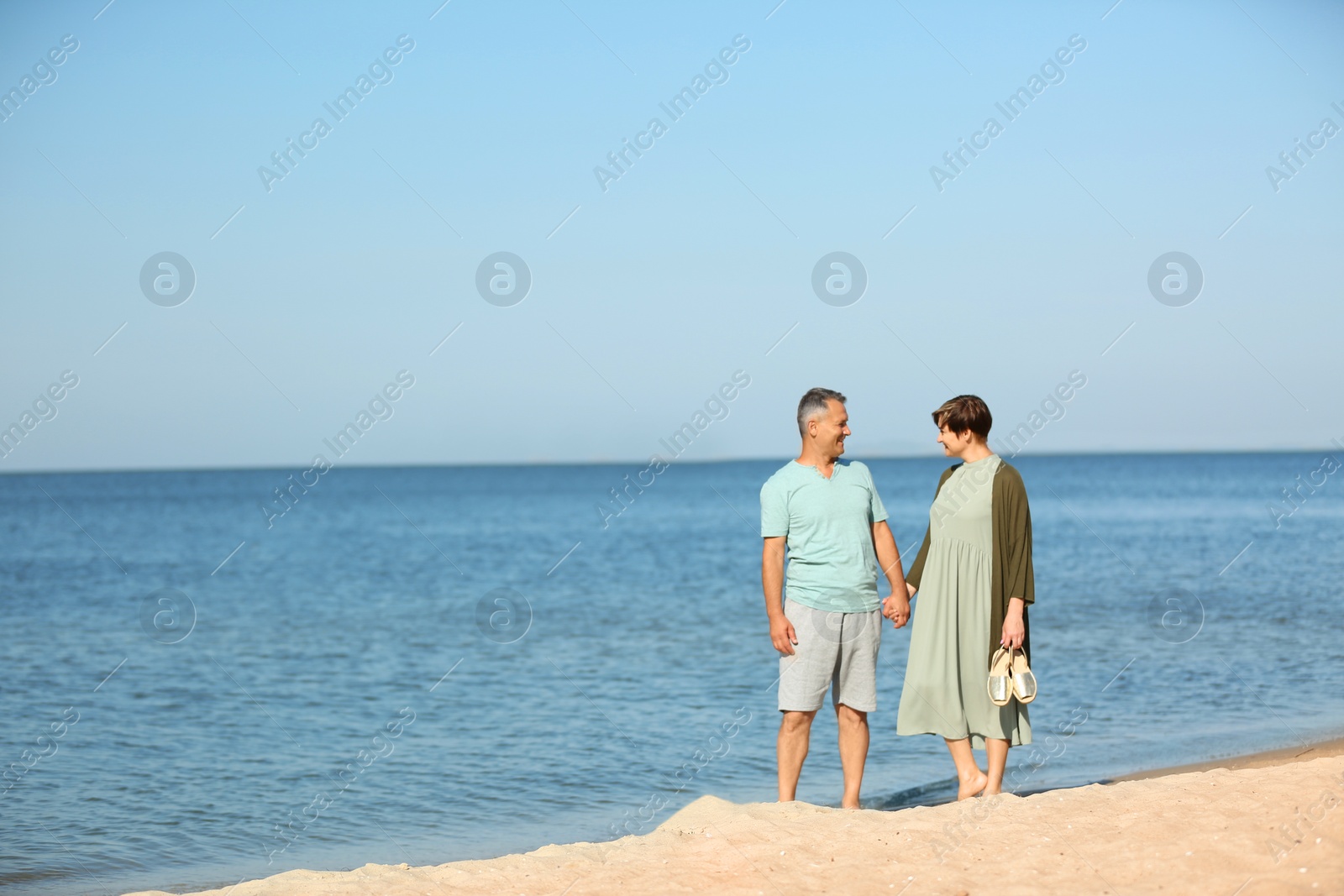 Photo of Happy mature couple walking at beach on sunny day