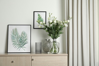 Photo of Decorative vases and pictures on commode indoors