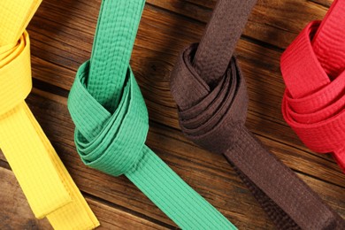 Colorful karate belts on wooden background, flat lay