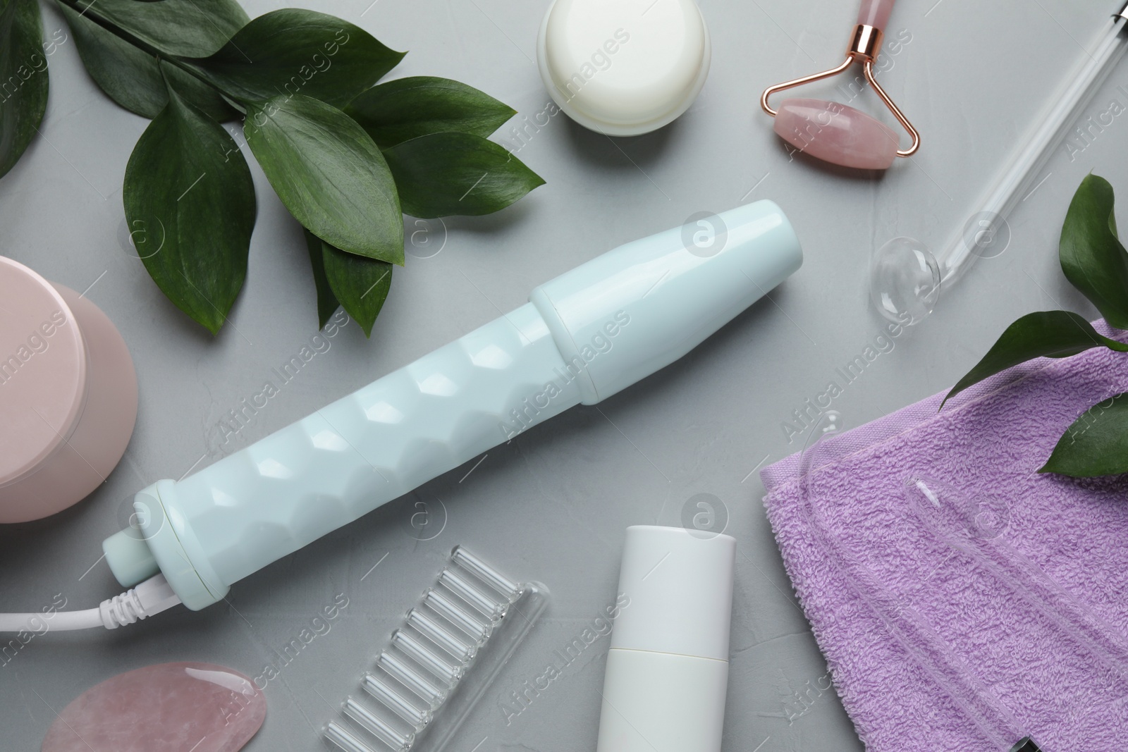 Photo of Flat lay composition with darsonval, rose quartz facial roller and gua sha on grey table