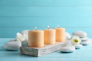 Composition with burning candles, spa stones and flowers on table. Space for text