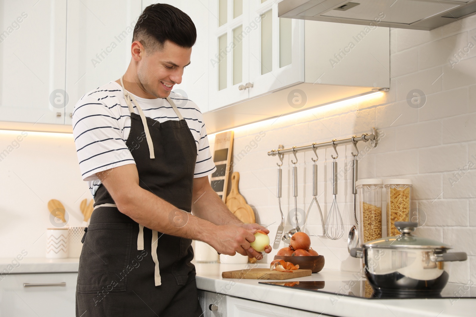 Photo of Man peeling onion at kitchen counter. Preparing vegetable