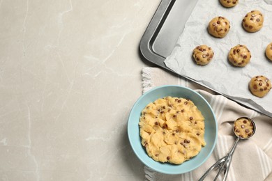 Photo of Bowl with dough and uncooked chocolate chip cookies on light grey table, flat lay. Space for text