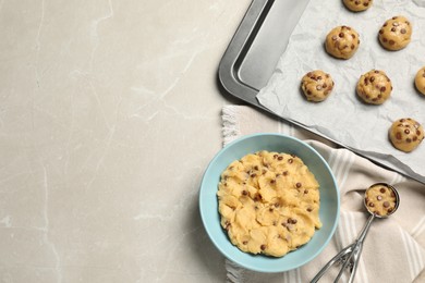 Bowl with dough and uncooked chocolate chip cookies on light grey table, flat lay. Space for text