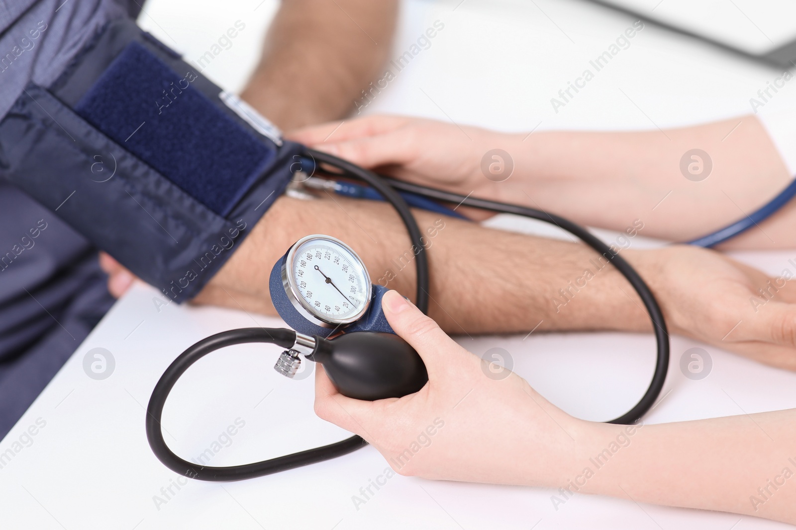 Photo of Doctor checking blood pressure of man in clinic, closeup