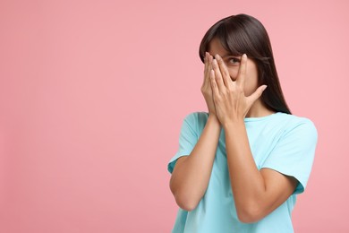 Embarrassed woman covering face with hands on pink background, space for text
