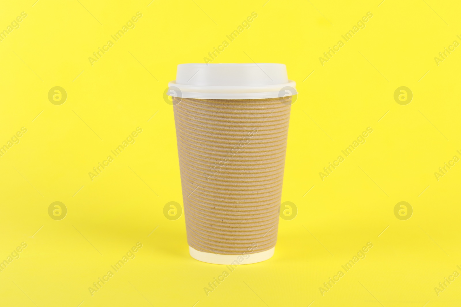 Photo of Paper cup with plastic lid on yellow background. Coffee to go