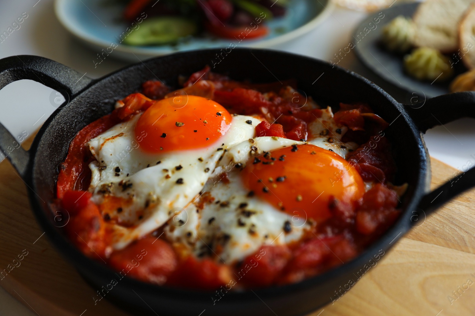 Photo of Tasty Shakshouka served in pan on table, closeup