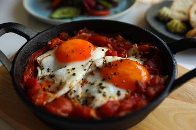 Tasty Shakshouka served in pan on table, closeup