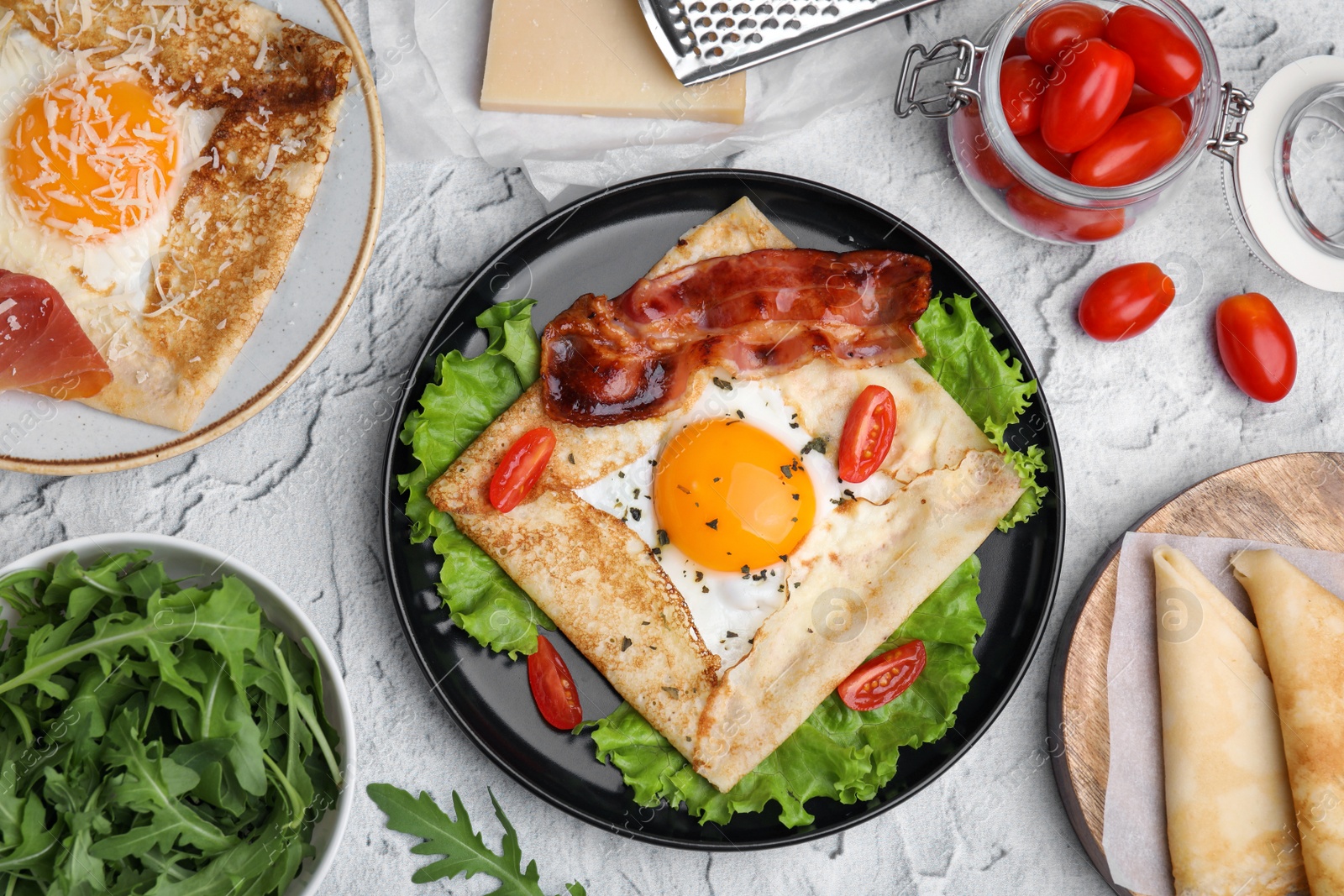 Photo of Delicious crepe with egg served on light gray textured table, flat lay. Breton galette