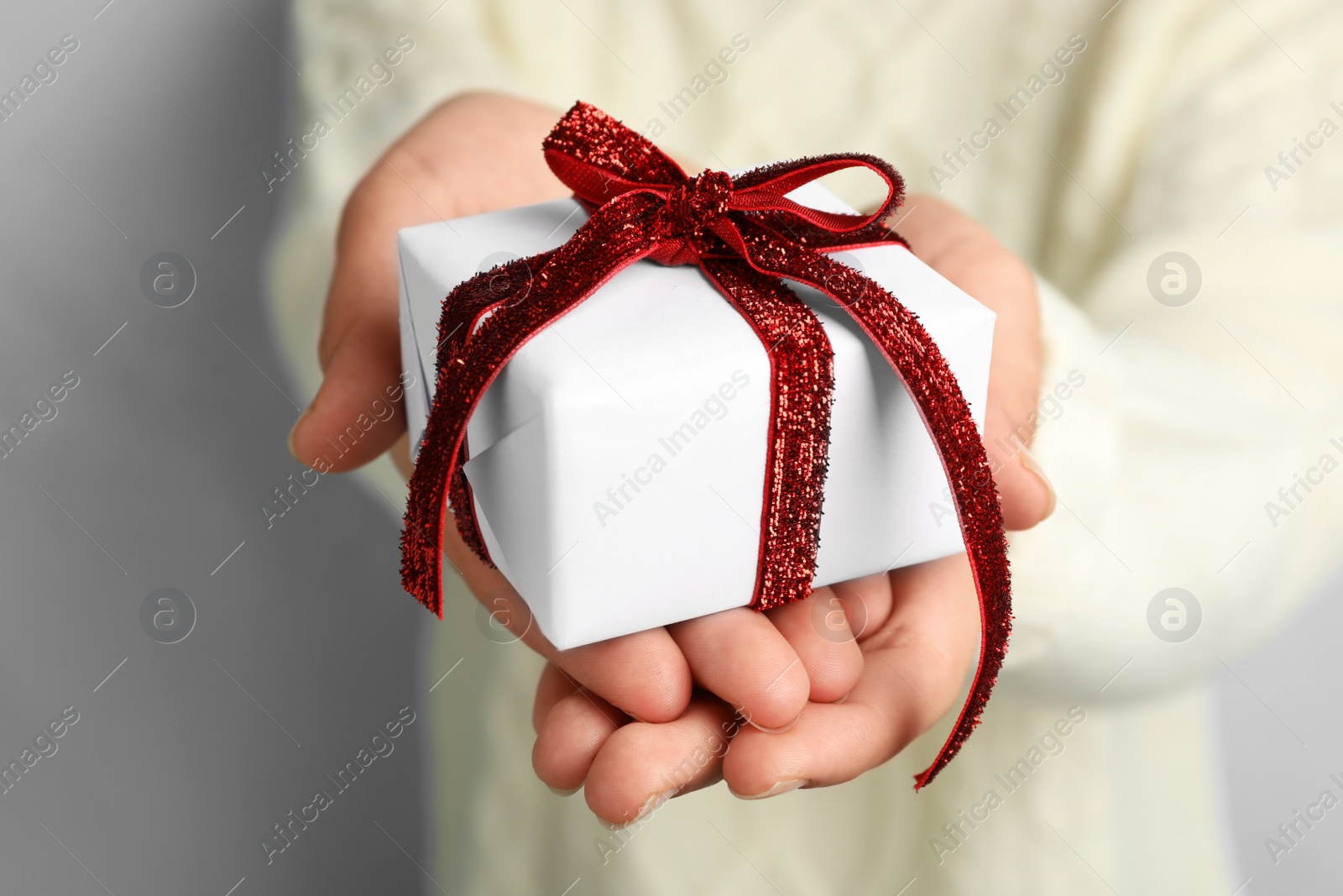 Photo of Woman holding beautiful Christmas gift on light blue background, closeup